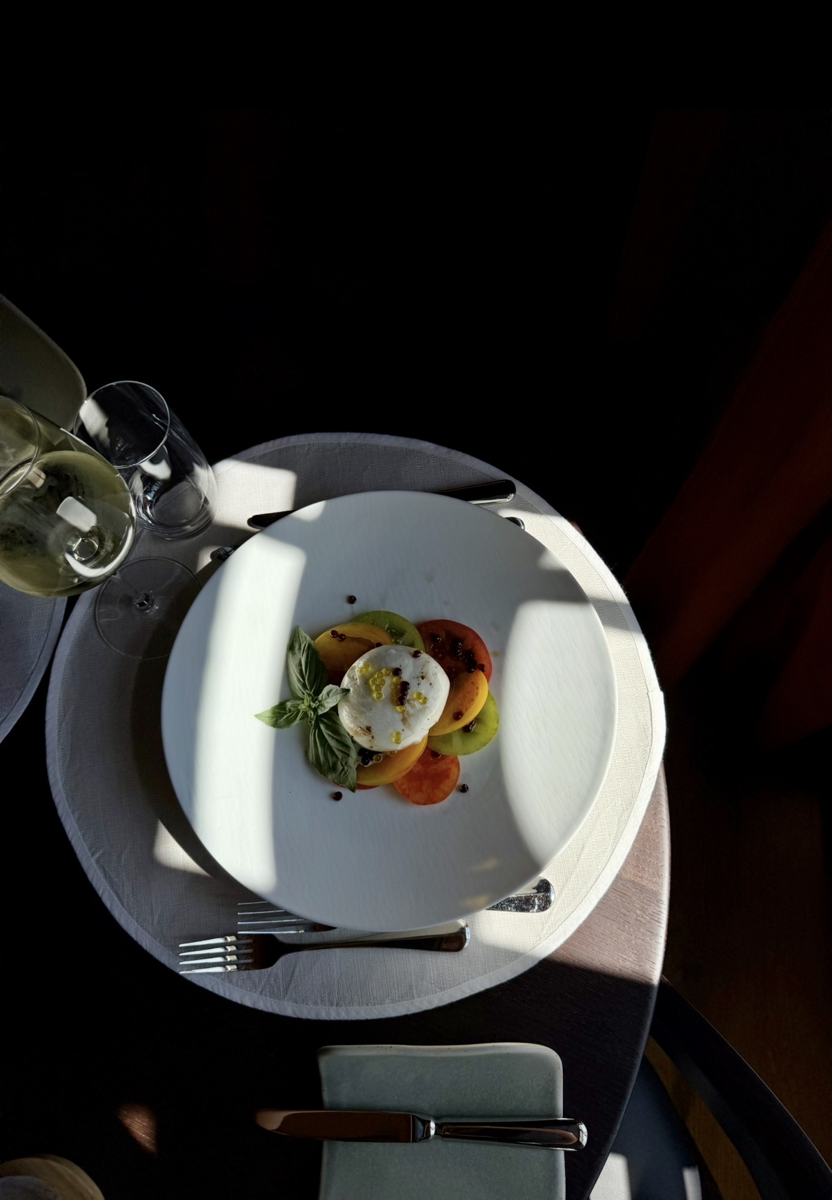 Burrata mit bunten Tomaten und Basilikum auf weissem Teller